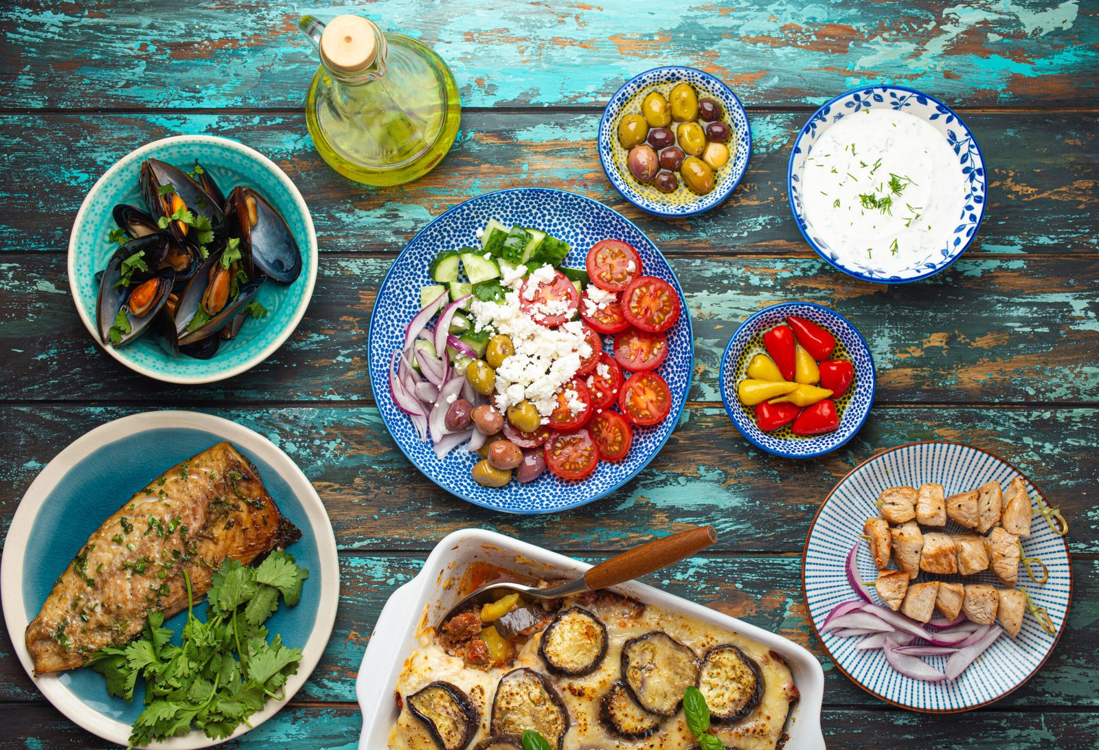 Assorted Greek dishes on rustic wooden background from above, moussaka, grilled fish, souvlaki, greek salad, steamed mussels with herbs, appetizers of Greece from above